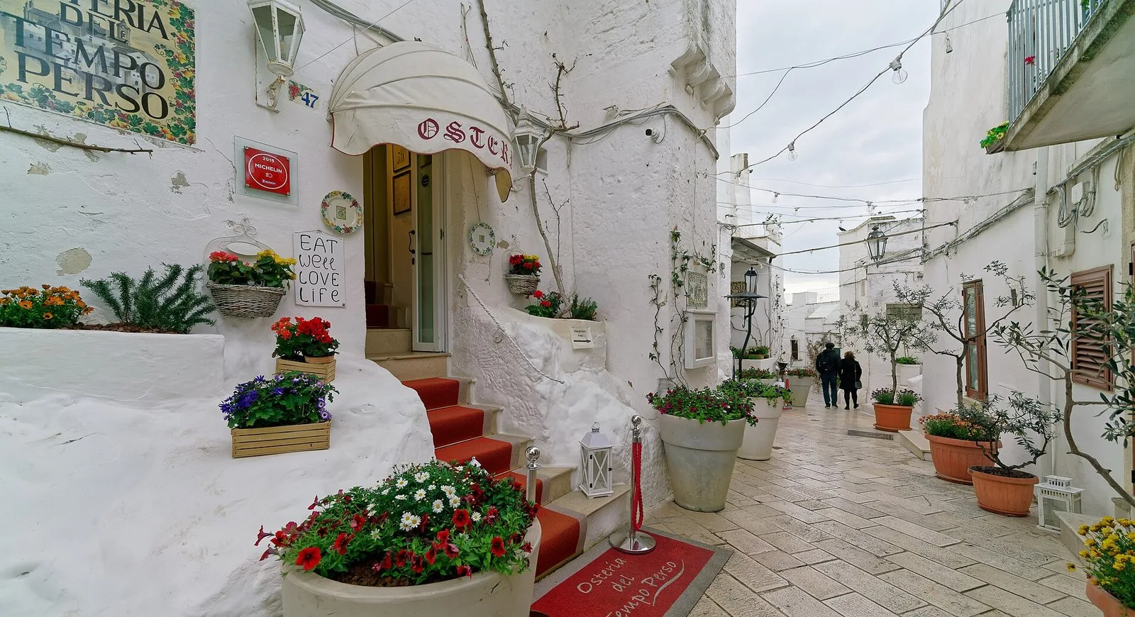 Un vicolo del centro storico di Ostuni, con fiori e insegne